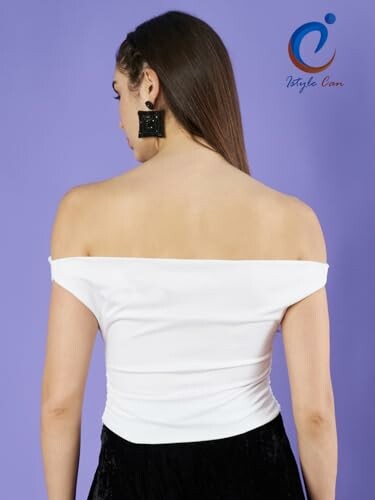Woman in off-shoulder white top with black skirt, back view.